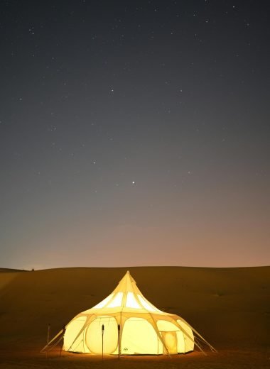 pexels-photo-11181888-11181888 A glowing glamping tent set against a starry night sky in the Dubai desert.